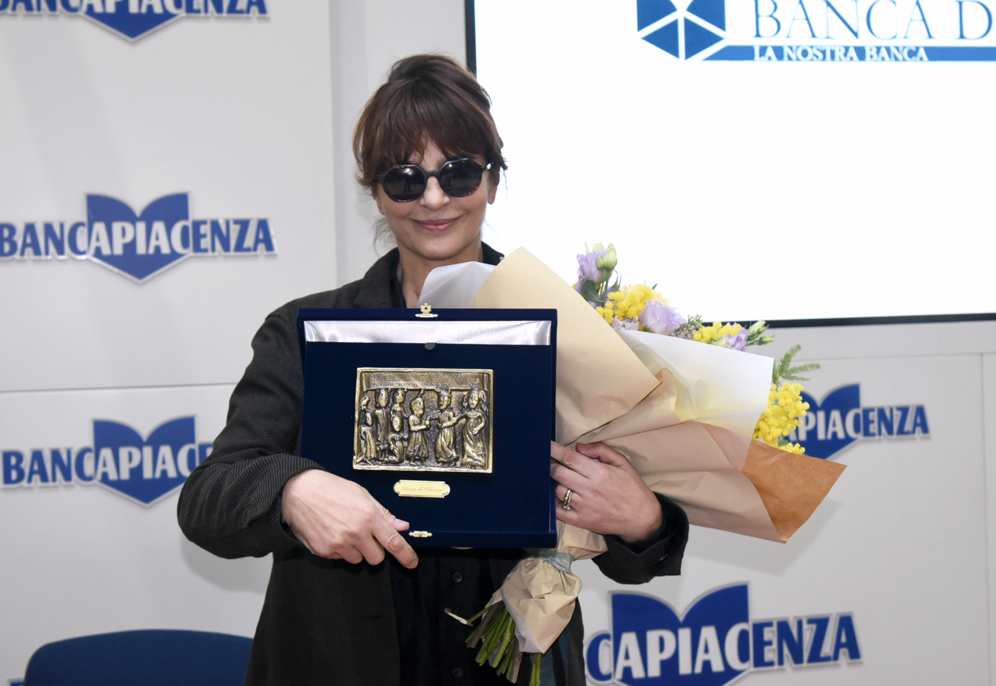 Fiori per la Festa della donna e un ricordo della Banca di Piacenza per l'attrice toscana